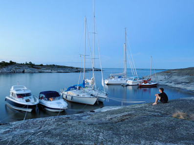Veneet satamassa, poika istuu kalliolla, venesammutin